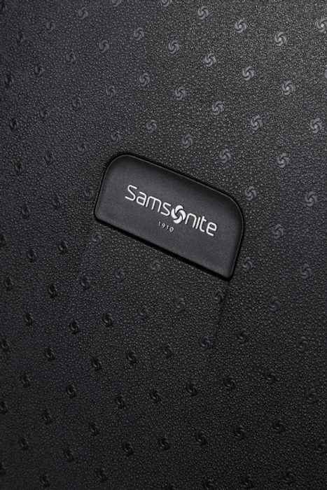 Designové logo značky Samsonite na přední straně kufru SAMSONITE, DESIGNOVÉ LOGO ZNAČKY SAMSONITE NA PŘEDNÍ STRANĚ KUFRU - SKOŘEPINOVÉ KUFRY - CESTOVNÍ KUFRY A TAŠKY