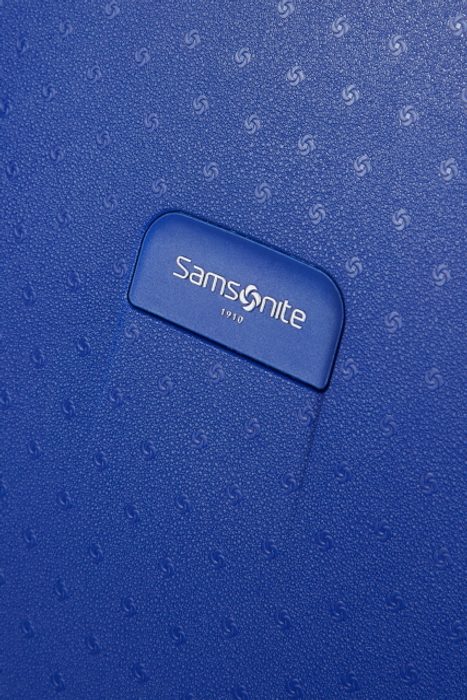 Designové logo značky Samsonite na přední straně kufru SAMSONITE, DESIGNOVÉ LOGO ZNAČKY SAMSONITE NA PŘEDNÍ STRANĚ KUFRU - SKOŘEPINOVÉ KUFRY - CESTOVNÍ KUFRY A TAŠKY