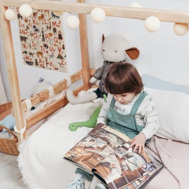 montessori detská izba - dieťa si číta knihu na posteli