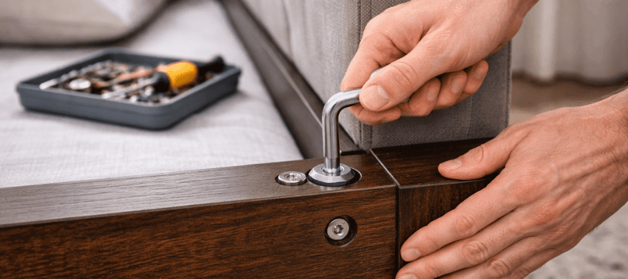 Dotahování povolených šroubů na rámu dřevěné postele imbusovým klíčem jako řešení vrzání