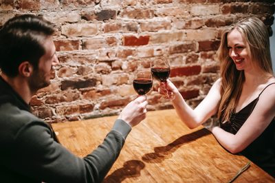 prvé rande, dvojica pri stole v reštaurácií si štrngá s pohárom s červeným vínom