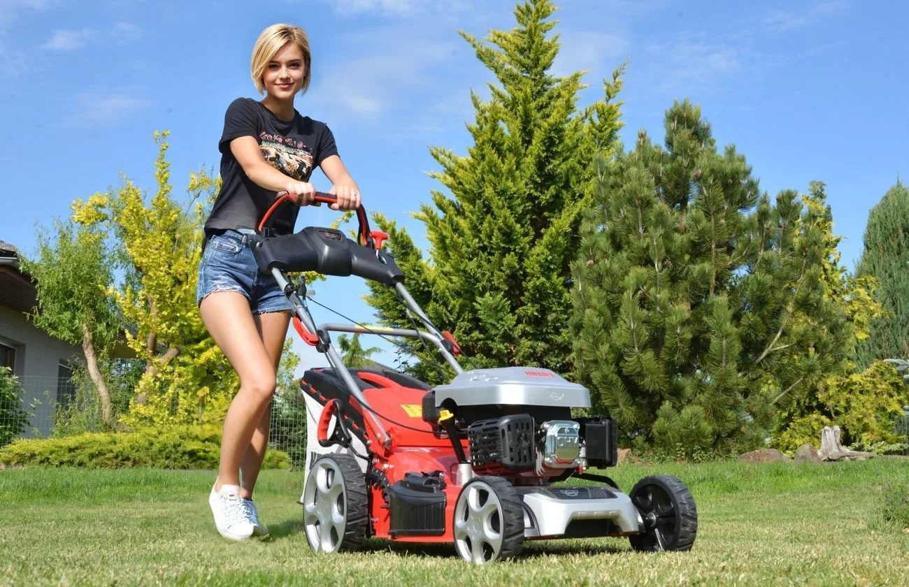 žena s kosačkou hecht na trávniku počas slnečného dňa