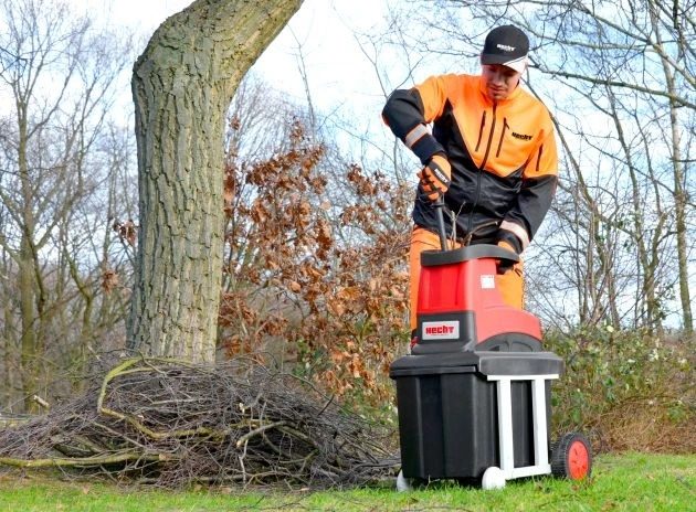 Muž v pracovnom oblečení vkladajúci vetvu do drviča vetiev HECHT