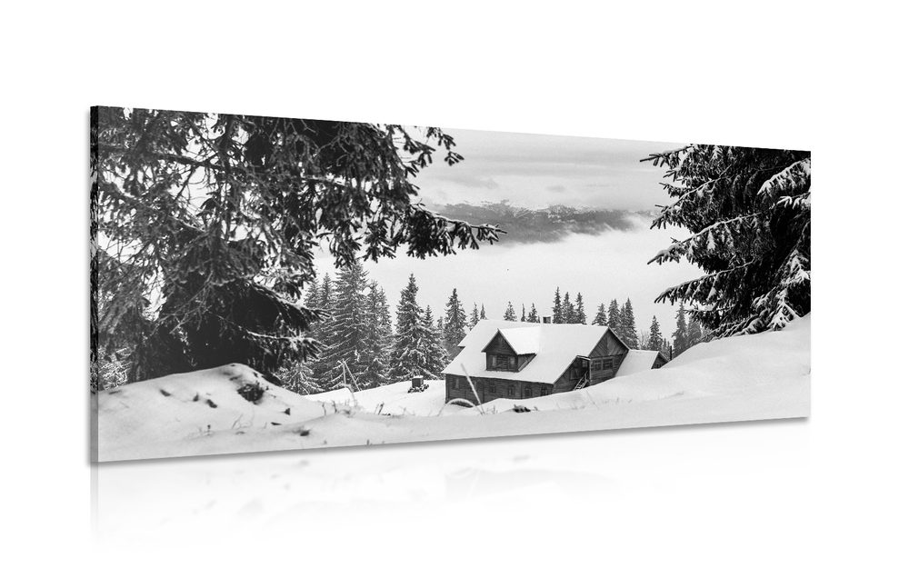 Obraz drevený domček pri zasnežených boroviciach v čiernobielom prevedení