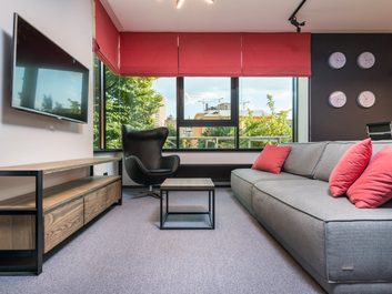 sivá obývačka, červené závesy, červené dekoratívne vankúšiky