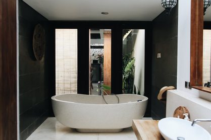 moderná kúpeľňa s čiernym obkladom, drevom a bielou voľne stojacou vaňou