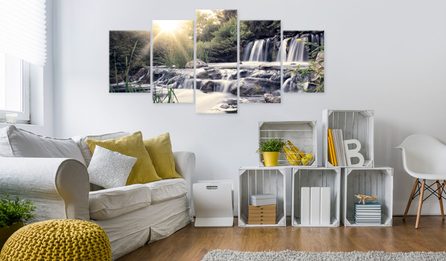 obývačka v štýle hygge s bielou sedačkou, žlté e svetlé vankúšiky, biely nábytok a obraz vodopádu