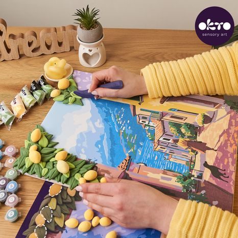 RUKA NANÁŠEJÍCÍ MODELOVACÍ HMOTU NA PLÁTNO S CITRONY