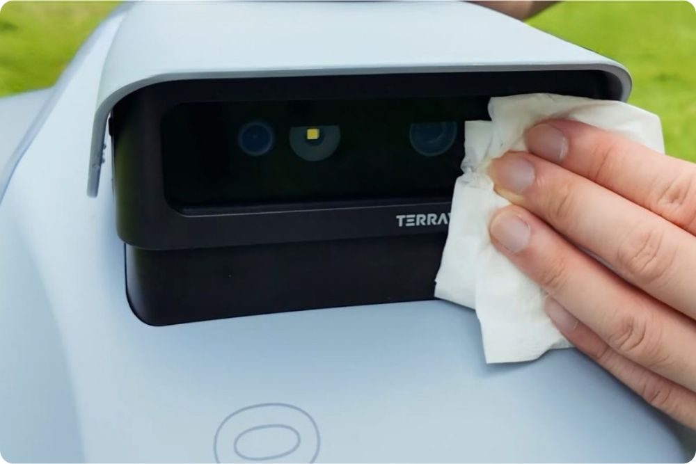 Čištění kamery a senzorů robotické sekačky vlhkou utěrkou při zazimování