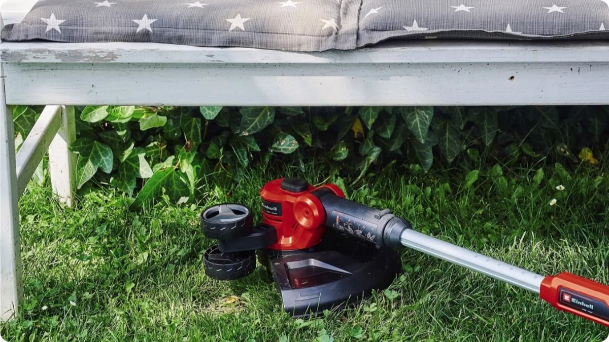 Dosekávání trávy vyžínačem pod zahradní lavičkou