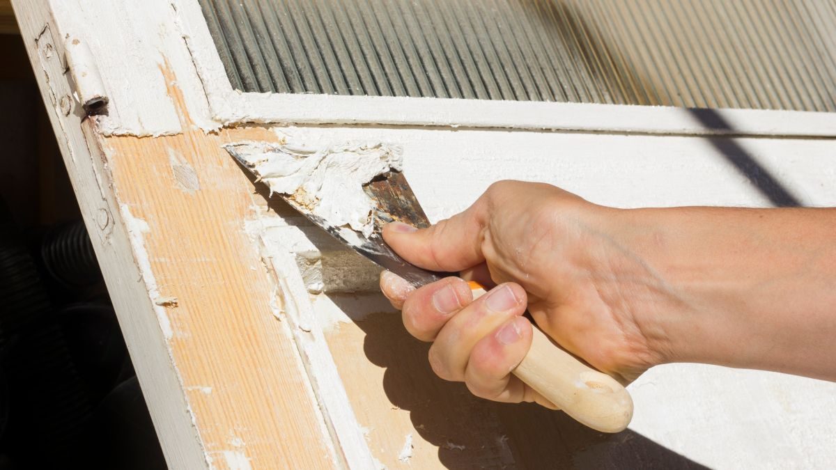 odstraňování staré barvy z dřevěného rámu pomocí špachtle