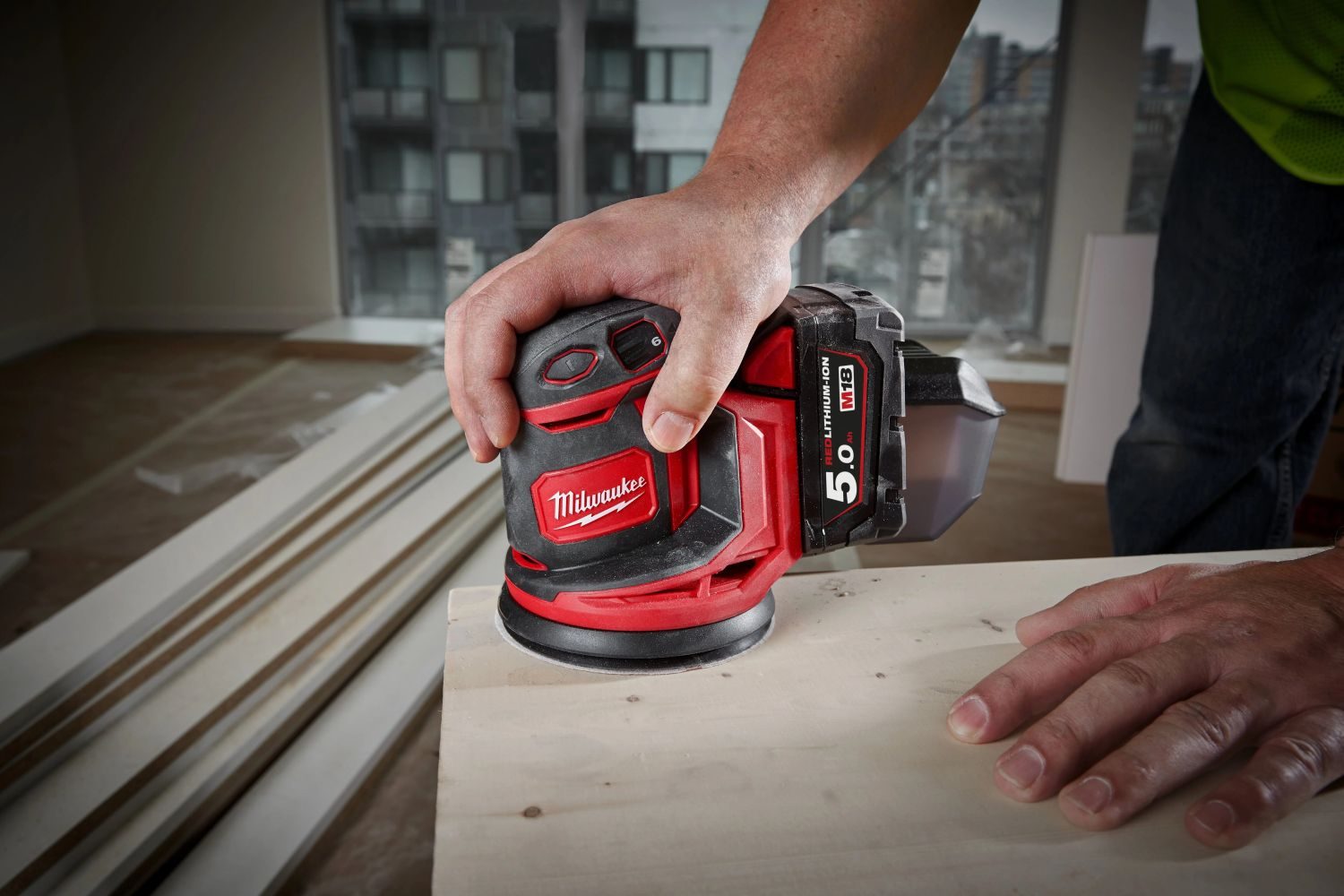 akumukátorová excentrická bruska Milwaukee při broušení dřevěné desky