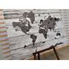 Obraz čiernobiela mapa sveta so symbolickými zvieratami na drevenom podklade