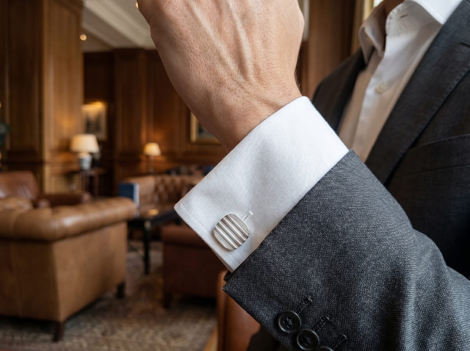 detail kulatých manžetových knoflíčků na bílé košili při elegantním outfitu
